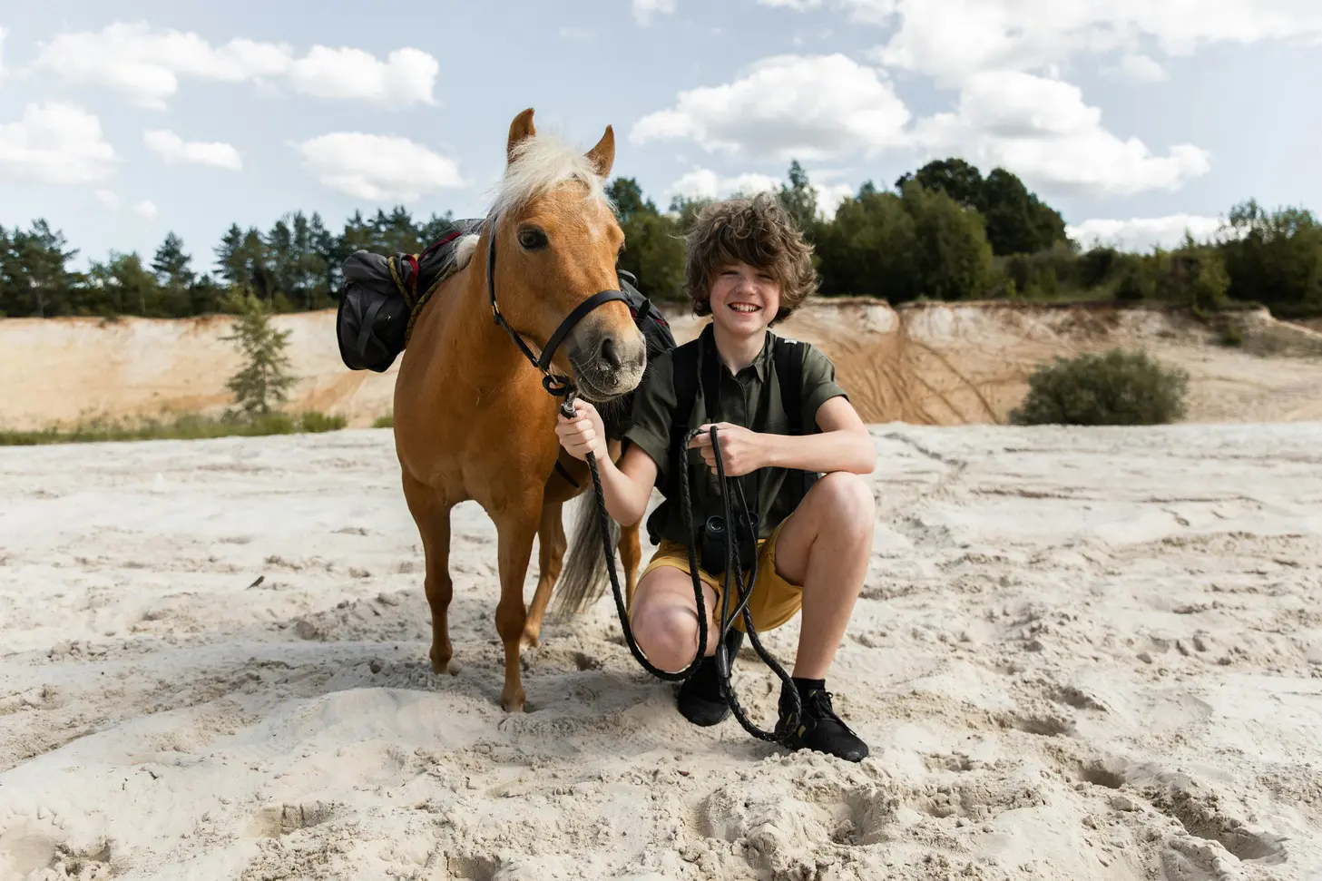 A person kneeling down next to a horse.